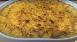 Golden-brown baked mac and cheese in a white casserole dish, with a crispy cheese crust.